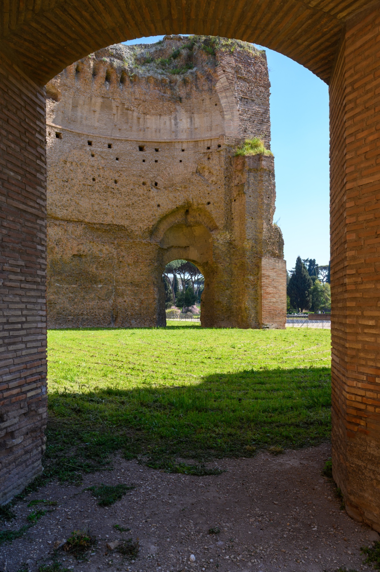 View through a brick arch toward ancient ruins and greenery