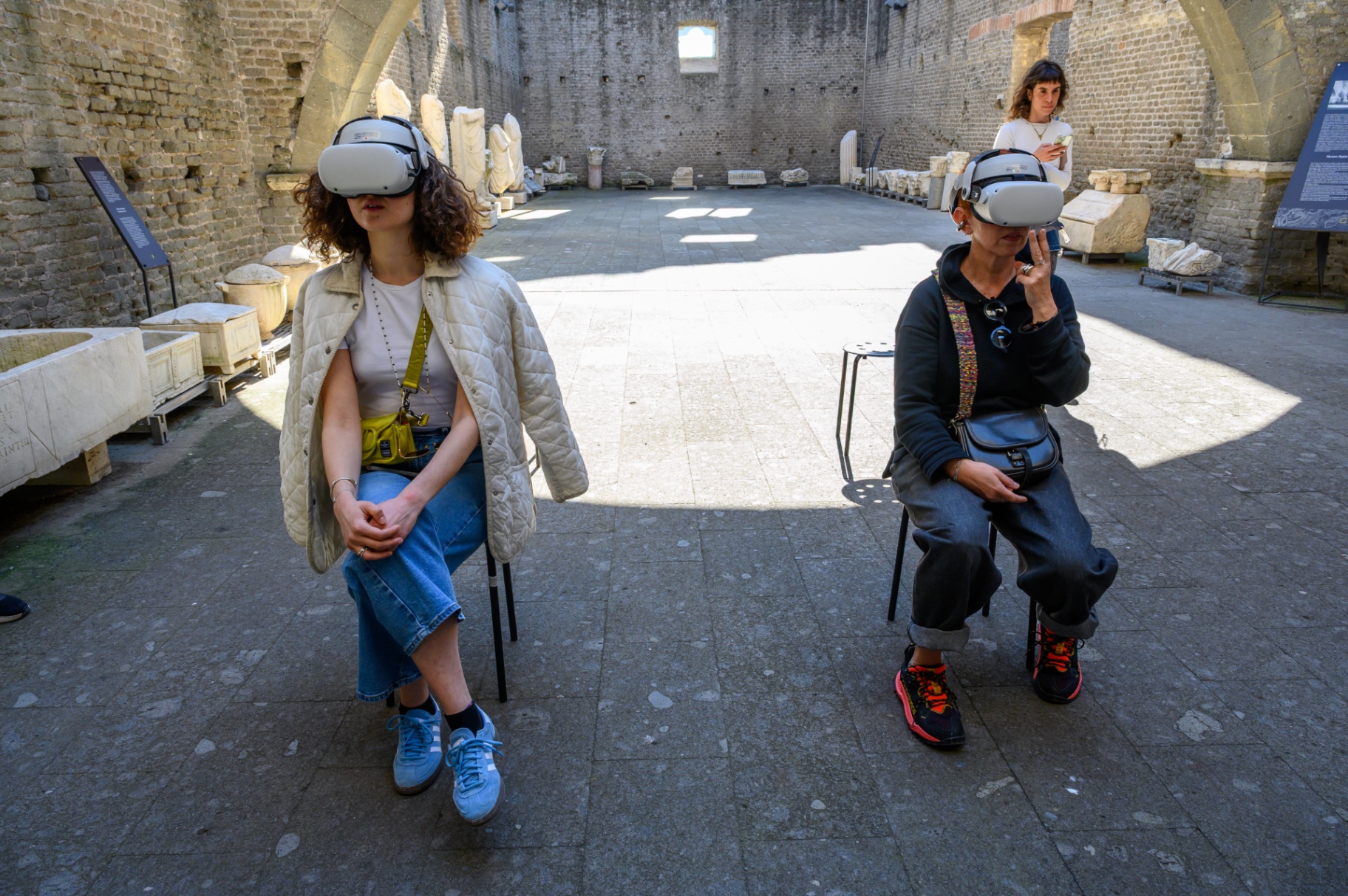 Two guests with VR headsets seated inside ancient stone hall