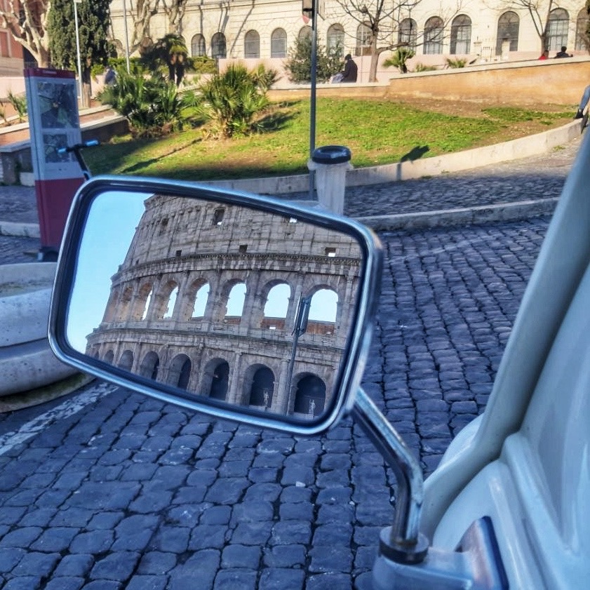 Colosseum reflected in the side mirror of a vintage van